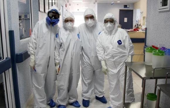 Médicos posan con sus trajes de protección covid-19