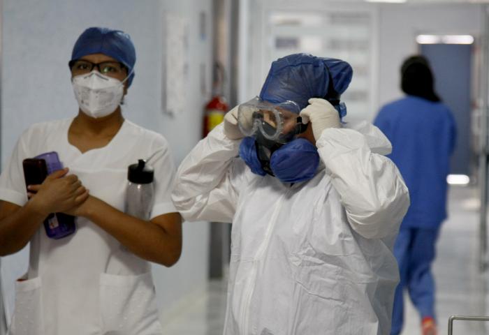 Mujer médico se coloca lentes de protección contra covid-19