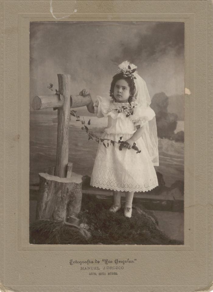 Fotografía de niña posando junto a una cruz
