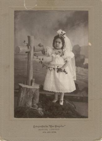 Fotografía de niña posando junto a una cruz