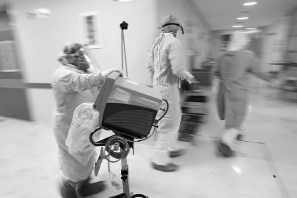 Médico traslada monitor por pasillo del hospital 