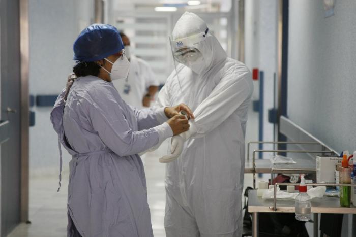 Médico ajusta traje de protección de su compañero