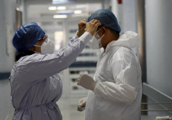 Médico ayuda a otro a ajustar su traje de protección antes de ingresar al área COVID-19