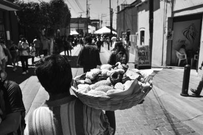 Hombre con canasta de pan camina por la calle Aquiles Serdán