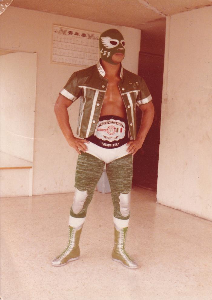 Bobby Lee de cuerpo entero con el cinturón de campeón mundial wélter